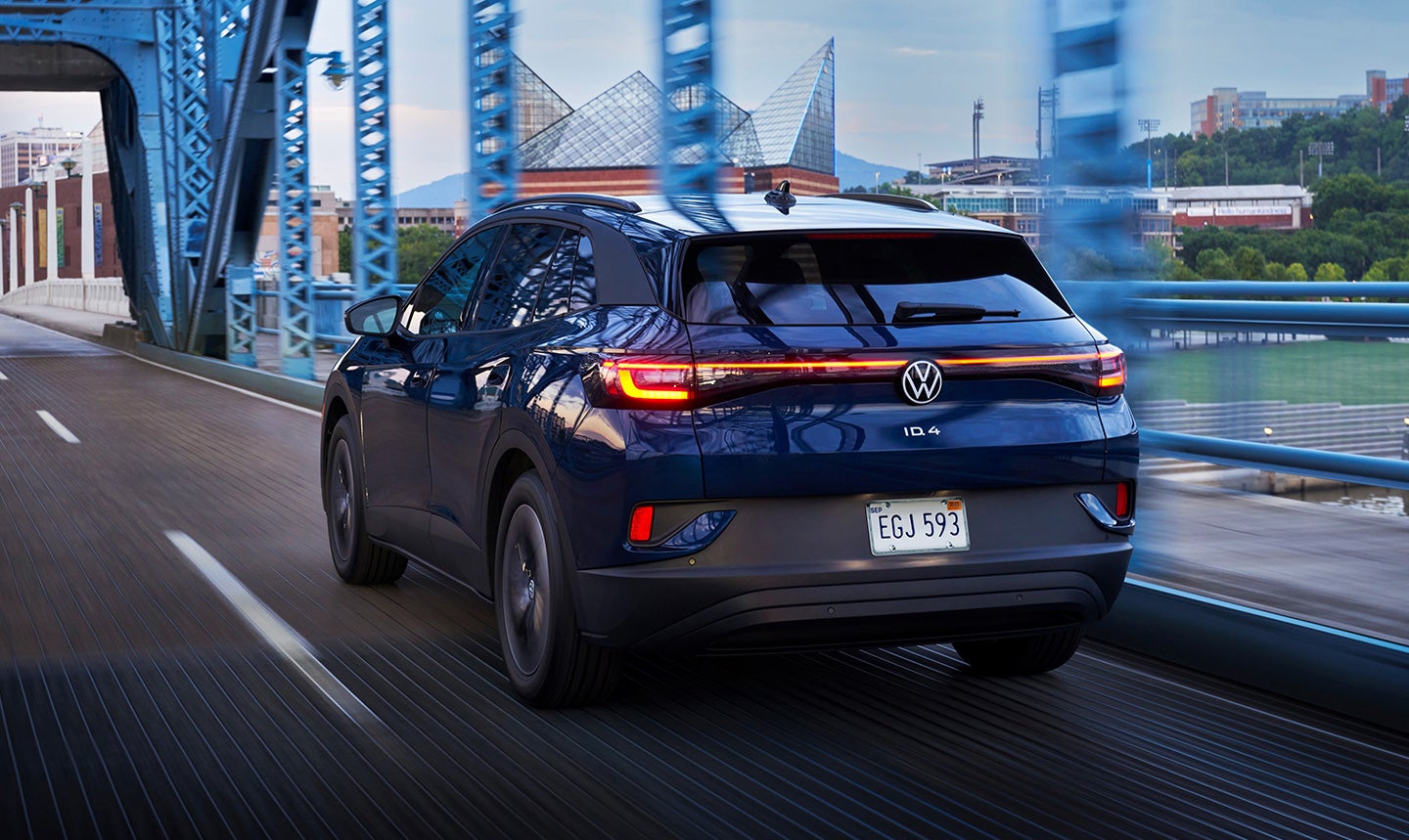 An ID.4 Pro Standard shown in Tourmaline Blue Metallic drives through a bridge at dusk.